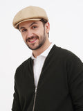 Man wearing sand linen newsboy cap three-quarter view black jacket