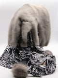 Three-quarter back view sapphire mink fur hat hood with blue watercolor leopard scarf and pompons
