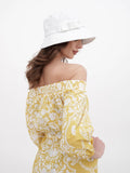 Back view of woman in white bucket hat and yellow floral dress
