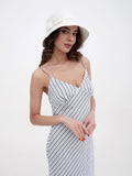 Woman in white bucket hat and striped dress standing outdoors