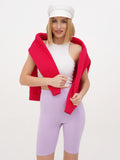 Woman in white linen baker boy cap, red top and lilac shorts full length