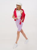 Woman walking in white linen Breton cap with red top and lilac shorts