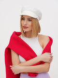 Woman wearing white linen Breton cap with red wrap top, holding scarf