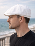 Man wearing white linen newsboy cap side view sea promenade summer