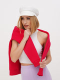 Close-up of woman in white linen newsboy cap wrapped in red scarf