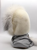 Three-quarter view white mink hood with arctic fox trim showing grey fabric scarf body and pompon