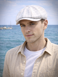 Man adjusting white plaid linen baker boy cap coastal summer setting