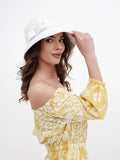 Woman in white sun hat adjusting brim, yellow floral dress