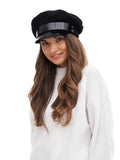 Portrait view woman in black cashmere captain hat with patent visor