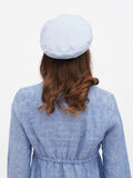 Close-up top view of women's blue linen beret showing structured flat crown and linen weave detail