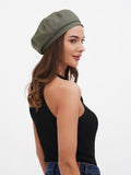Women's khaki beret hat full body view with black top and blue flared trousers, casual summer look