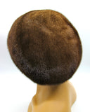 Women's pastel brown mink fur beret side profile close-up showing soft caramel fur texture and voluminous crown detail