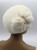 Women's white mink beret with large flower lower angle view showing crown base and petal structure