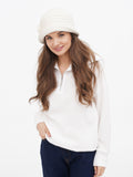 Woman standing in white hoodie, navy trousers and white sneakers wearing wool cloche hat