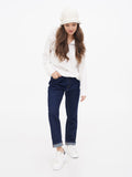 Woman standing in white hoodie, navy trousers and white sneakers wearing wool cloche hat