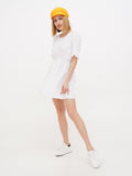 Back side view of woman wearing yellow linen Breton cap and white dress