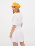 Woman in yellow linen newsboy cap and white dress, full length front